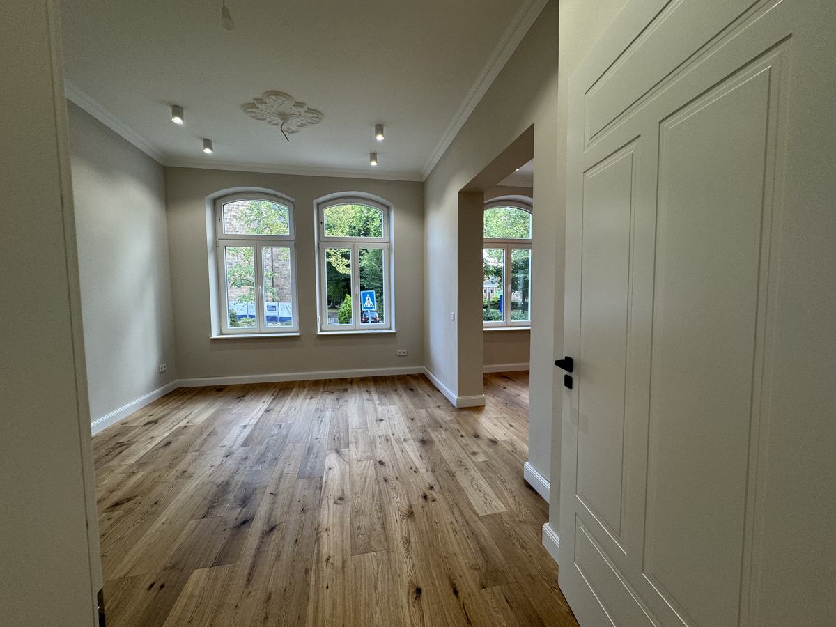 Wohnraum mit Jugendstil-Deckenrosette und Rundbogenfenstern