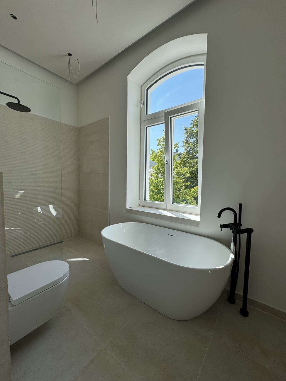 Freistehende Badewanne vor dem Rundbogenfenster