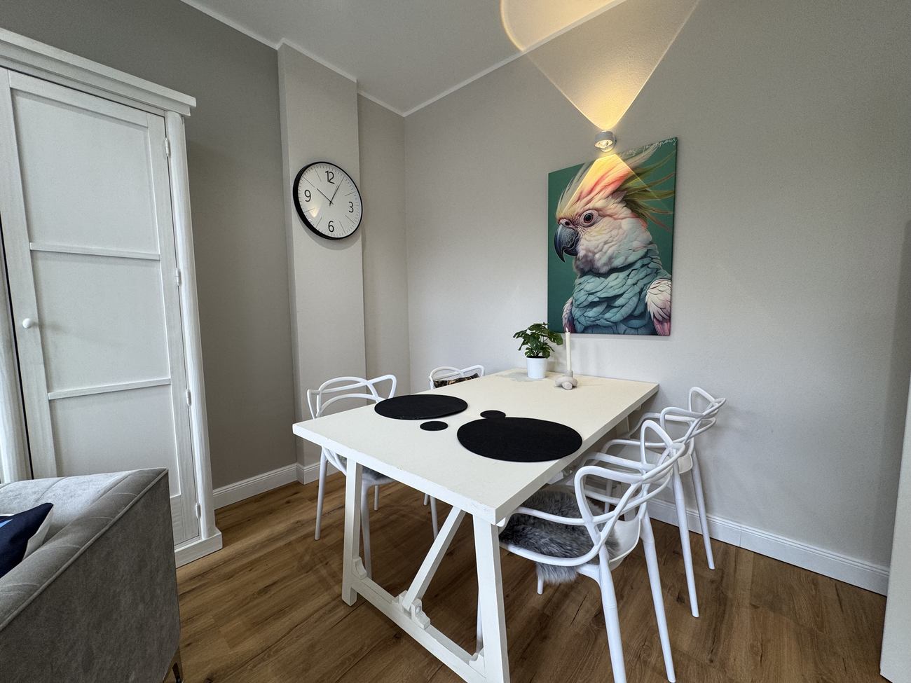 Essplatz mit weißem Tisch, Designerstühlen und Kunstdruck