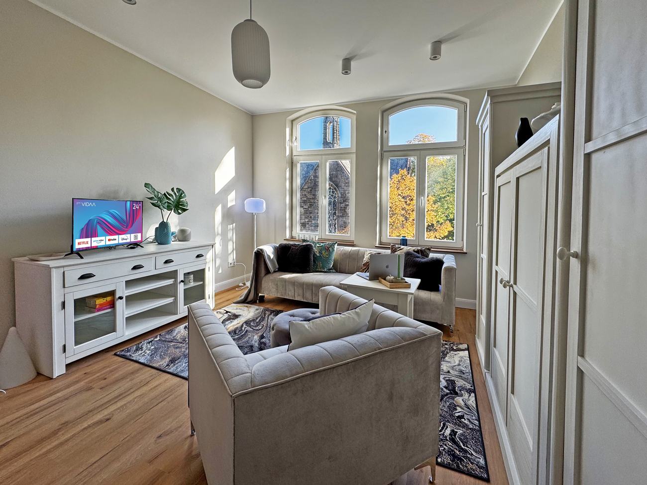 Atelierwohnung 3: Wohnraum mit Rundbogenfenstern und Blick zur Kirche
